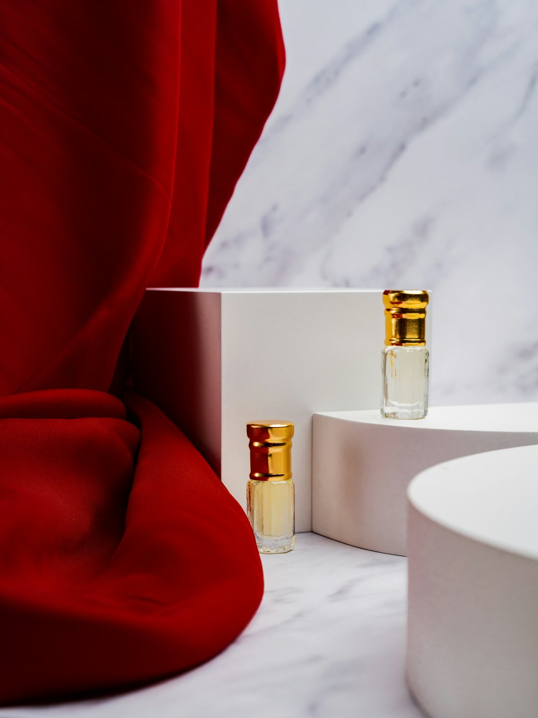 Two small clear glass perfume bottles on white stands.